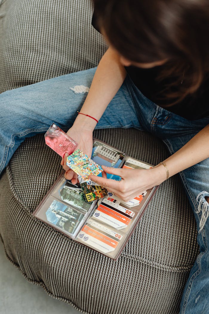 A young woman sits with a collection of colorful credit cards in an organizer, focusing on a vibrant card.